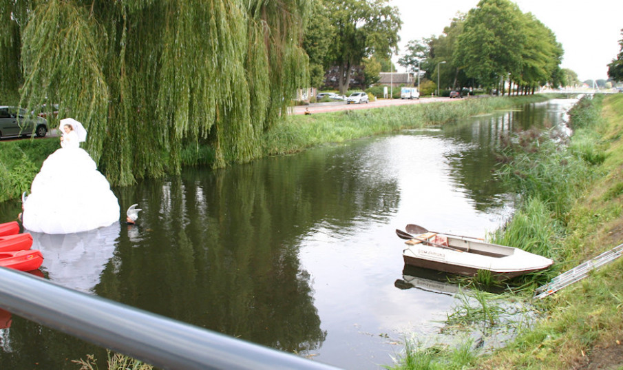 Uitzicht vanaf het Kerkbrugje op het water en de dame in de grote witte jurk, drijvend over het water.